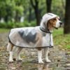 Transparent dog raincoat size 3XL on Beagle — PetzVibes Size 3XL transparent dog raincoat on a tricolor Beagle standing on wet park path, frosted TPU cape with black piping, soft hood, full side view