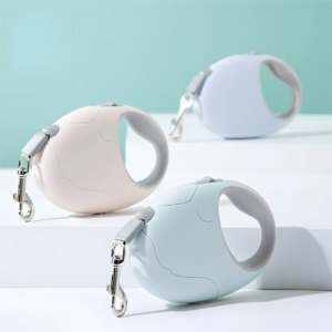 Three PetzVibes oval retractable dog leashes in white, blush pink, and sky blue arranged on white display surfaces with a soft teal background.