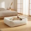plush-ribbed-calming-pet-bed-cats-dogs-white-french-bulldog-japandi-bedroom.jpg French Bulldog resting in a PetzVibes white plush ribbed calming pet bed on a bamboo mat floor in a serene Japandi bedroom