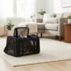 Cat peeking out of a black PetzVibes pet carrier in a living room, grey carrier beside it