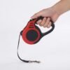 Retractable Dog Leash for Small Dogs Product Hand holding a red and black PetzVibes bone-print retractable dog leash, studio product shot